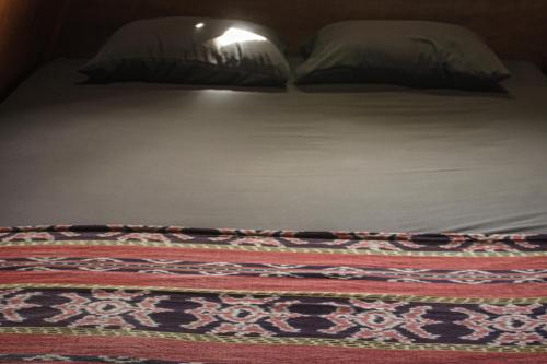 a bed with two pillows and a rug on it at Sinuan homestay- Jabu 02 in Pandanga