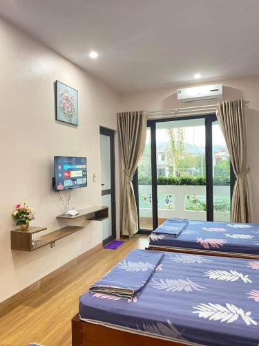 a bedroom with two beds and a tv and a window at GiaBinh Homestay in Cao Bằng