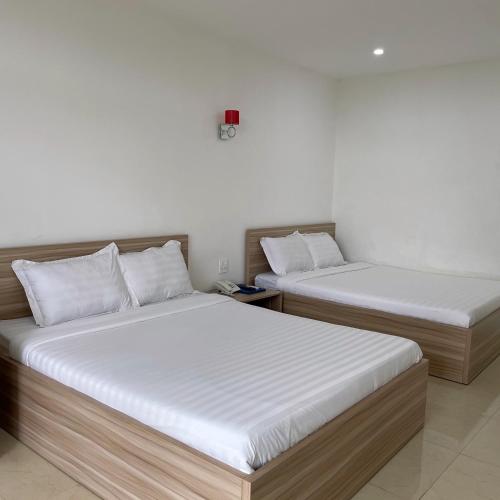 two beds in a room with white walls at Homestay Tulip Garden Bảo Lộc in Bao Loc