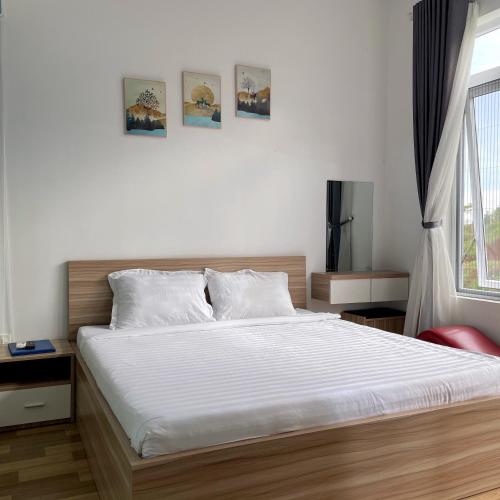 a bedroom with a bed with white sheets and a window at Homestay Tulip Garden Bảo Lộc in Bao Loc