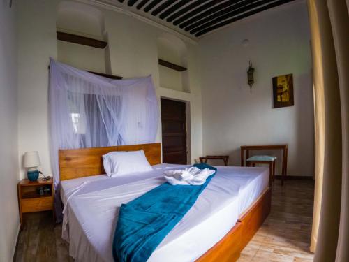 a bedroom with a bed with a blue blanket on it at Aurelia Zanzibar in Ngambo