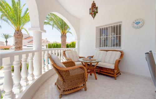 balcón con sillas, mesa y palmeras en Lovely Home In Ciudad Quesada-Rojales, en Rojales