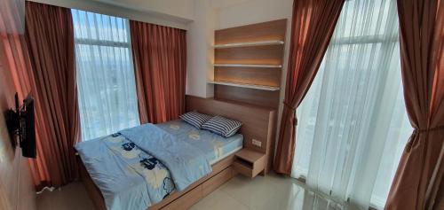 a bedroom with a bed in a room with windows at TreeParkCity apartments by WinsHome in Tangerang