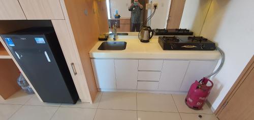 a small kitchen with a sink and a stove at TreeParkCity apartments by WinsHome in Tangerang