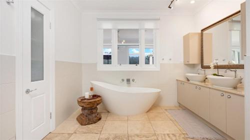 a white bathroom with two sinks and a tub at Cowley House in Dapto