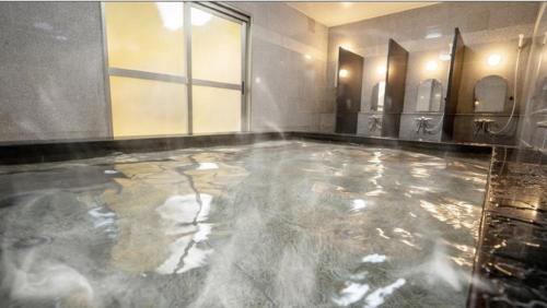 a bathroom with a pool of water on the floor at Hotel New Gaea Iizuka in Iizuka