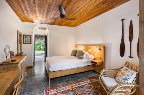 a bedroom with a bed and a wooden ceiling at The Nomadic Hotel in Nosara