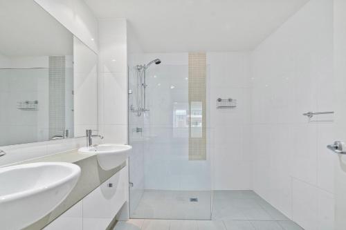 y baño blanco con lavabo y ducha. en Coast on Coral Luxury Apartment Unit 15, en The Entrance