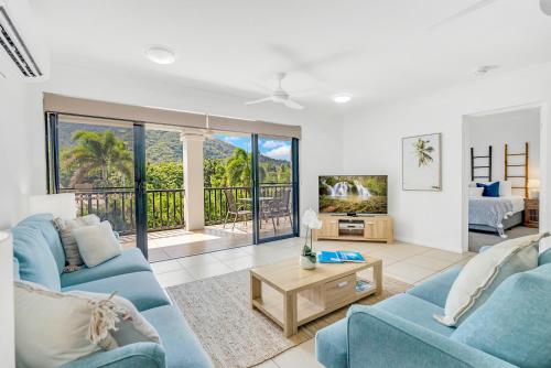 a living room with two blue couches and a tv at Elysium Apartments in Palm Cove