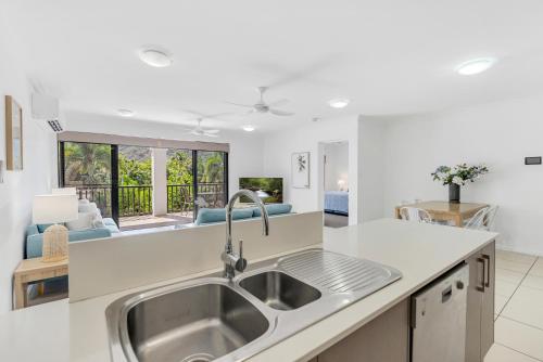 a kitchen with a sink and a living room at Elysium Apartments in Palm Cove