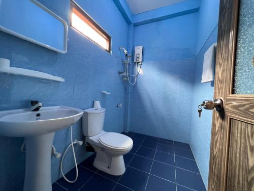 a blue bathroom with a toilet and a sink at Malika's Yellow House in Hikkaduwa