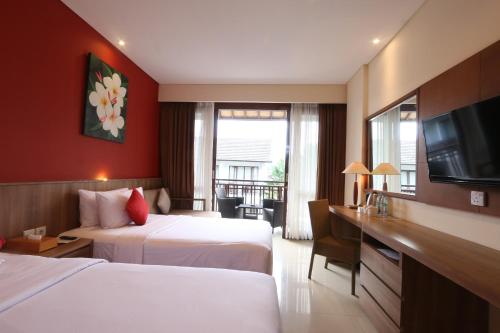 a hotel room with two beds and a flat screen tv at Grand La Walon Hotel in Legian