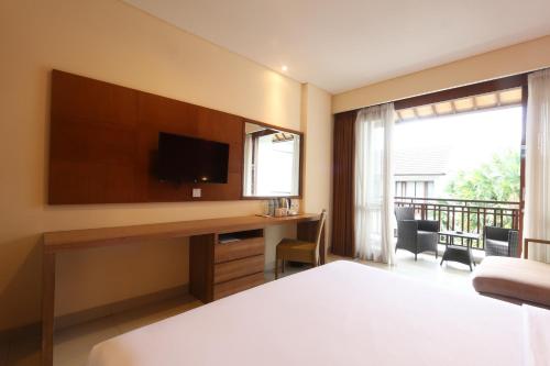 a bedroom with a bed and a desk with a television at Grand La Walon Hotel in Legian
