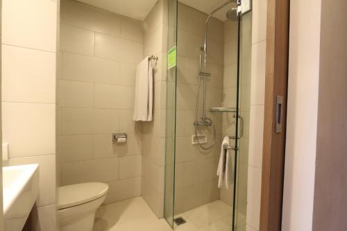 a bathroom with a toilet and a glass shower at Grand La Walon Hotel in Legian