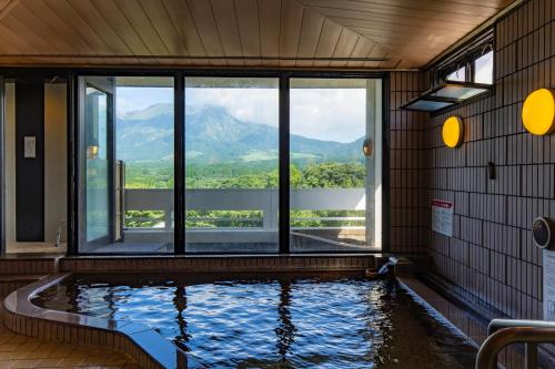 een zwembad met uitzicht op de bergen bij Kyukamura Minami-Aso in Takamori