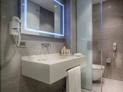 La salle de bains est pourvue d'un lavabo blanc et de toilettes. dans l'établissement TAV Airport Hotel Izmir, à Izmir