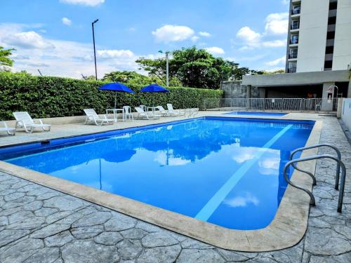 Una piscina con sillas y sombrillas al lado de un edificio. en Hermoso apto Sur de cali, en Cali