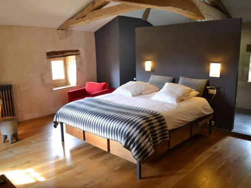 1 dormitorio con 1 cama grande y 1 silla roja en Gîte Beaulieu-sur-Sonnette, 2 pièces, 2 personnes - FR-1-653-219, en Beaulieu-sur-Sonnette