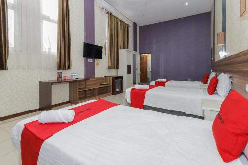 a hotel room with two beds and a television at RedDoorz Syariah @ Klojen Malang in Malang