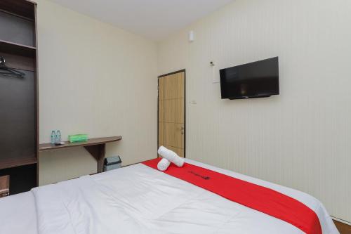 a room with a bed with a red and white blanket at RedDoorz Syariah @ Klojen Malang in Malang