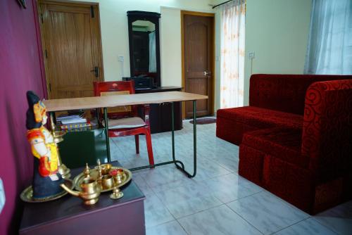 a living room with a table and a red chair at Vrindavan Suites Guruvayur in Guruvāyūr