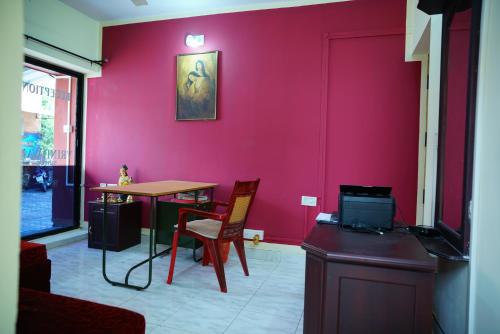 a room with a table and a red wall at Vrindavan Suites Guruvayur in Guruvāyūr