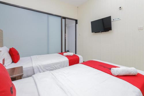 a hotel room with two beds and a flat screen tv at RedDoorz Syariah @ Klojen Malang in Malang