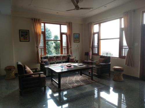 a living room with a table and chairs and windows at Villa Vikas Studio in Dharamshala