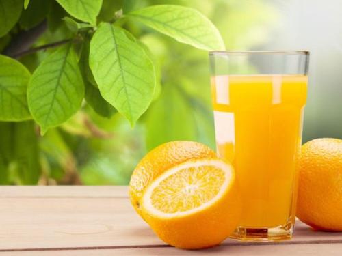 a glass of orange juice and oranges on a table at Grand Ciwareng Inn Hotel and Resort in Pasarsenen