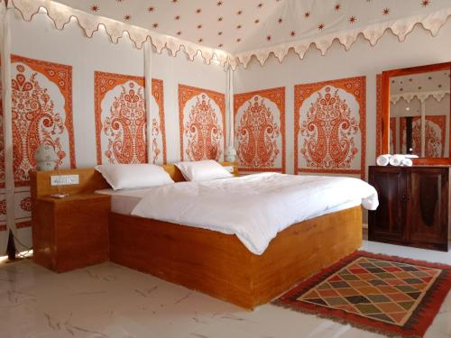 a bedroom with a bed in a room with orange and white wallpaper at Sunny Desert Camp in Kūri