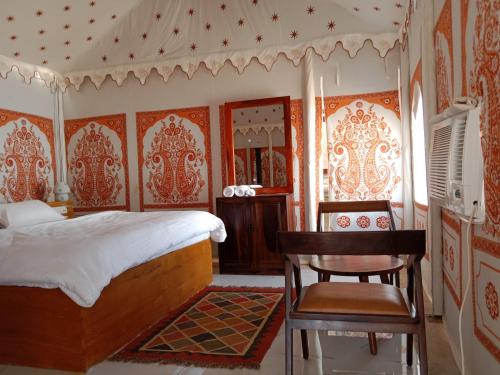 a bedroom with a bed and a table and a chair at Sunny Desert Camp in Kūri