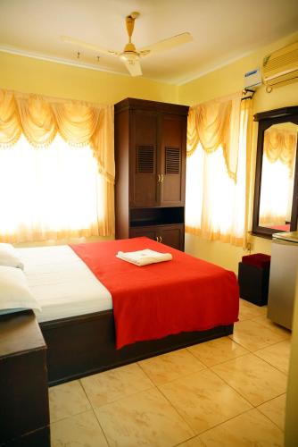 a bedroom with a bed with a red blanket at Vrindavan Suites Guruvayur in Guruvāyūr