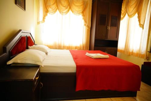 a bedroom with a bed with a red blanket and a window at Vrindavan Suites Guruvayur in Guruvāyūr