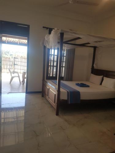 a bedroom with a canopy bed and a balcony at Sea Port Hiriketiya in Hiriketiya