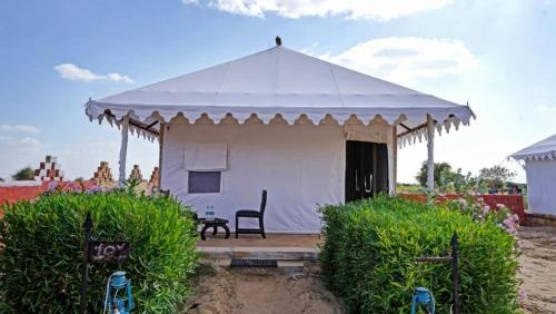 a white tent with a chair in a yard at Sunny Desert Camp in Kūri