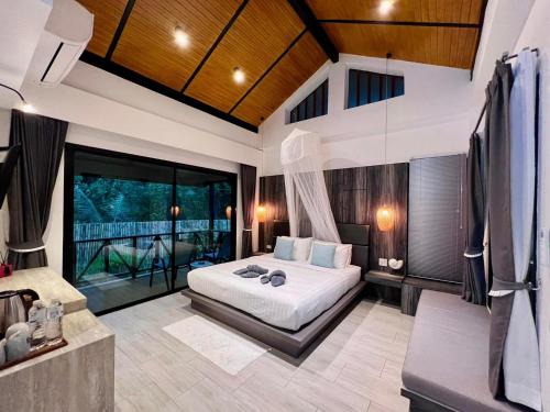 a bedroom with a bed and a large window at The Mantra Navi in Ko Lanta