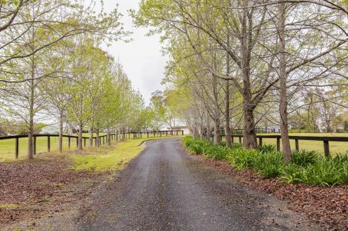 a dirt road with trees and a fence at Graelynn Farm in Mangrove Mountain