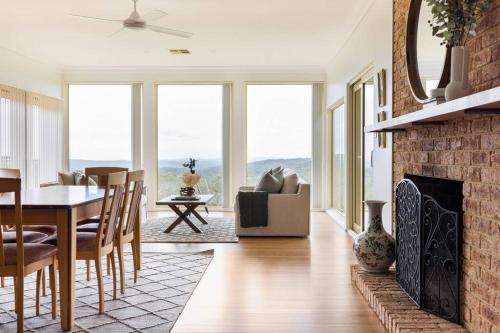 a living room with a brick fireplace and a table and chairs at Graelynn Farm in Mangrove Mountain