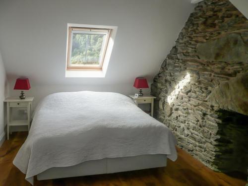 a bedroom with a bed and a stone wall at Sqlarran Cottage in Lochranza