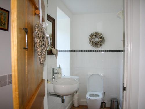 a white bathroom with a toilet and a sink at Sqlarran Cottage in Lochranza