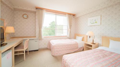a hotel room with two beds and a desk and a window at Kyukamura Rikuchu-Miyako in Miyako