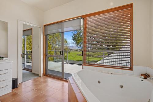 duża łazienka z wanną i dużym oknem w obiekcie Welcome Home - Hanmer Springs Holiday Home w mieście Hanmer Springs
