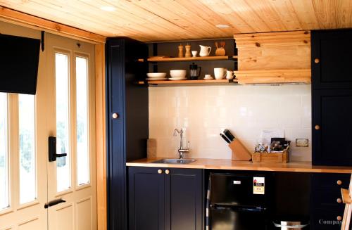 una cocina con armarios de color azul oscuro y fregadero en Compass Hut, en Melrose