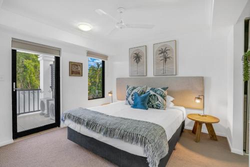 a bedroom with a large bed with blue pillows at Elysium Apartments in Palm Cove