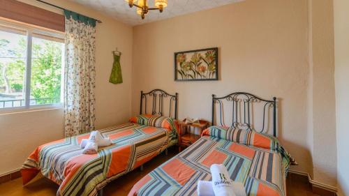 1 dormitorio con 2 camas y ventana en Vivienda Rural Pepe el del Aceite Trasmulas by Ruralidays, en Granada
