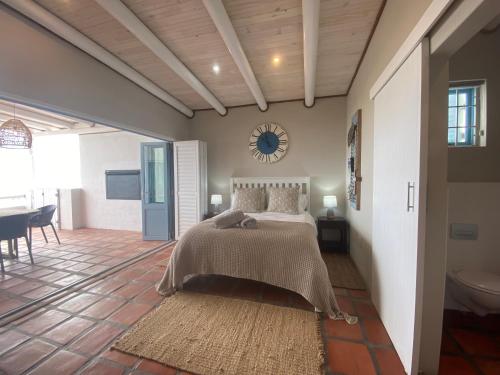 a bedroom with a bed and a clock on the wall at C'est la Vie in Paternoster