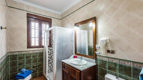 een badkamer met een wastafel, een douche en een spiegel bij La Villa del Lago Iznájar by Ruralidays in Iznájar