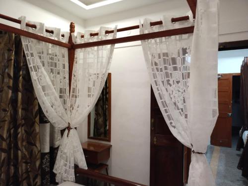 een bed met witte gordijnen in een kamer bij ROYAL STAY VINTAGE in Madurai
