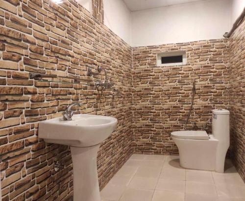 La salle de bains est pourvue d'un lavabo et d'un mur en briques. dans l'établissement The Glasshouse Hotel, à Kawasoti
