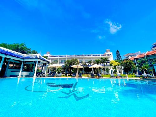 a large swimming pool with chairs and umbrellas at DYNASTY MUINE RESORT in Ấp Thiện Phước